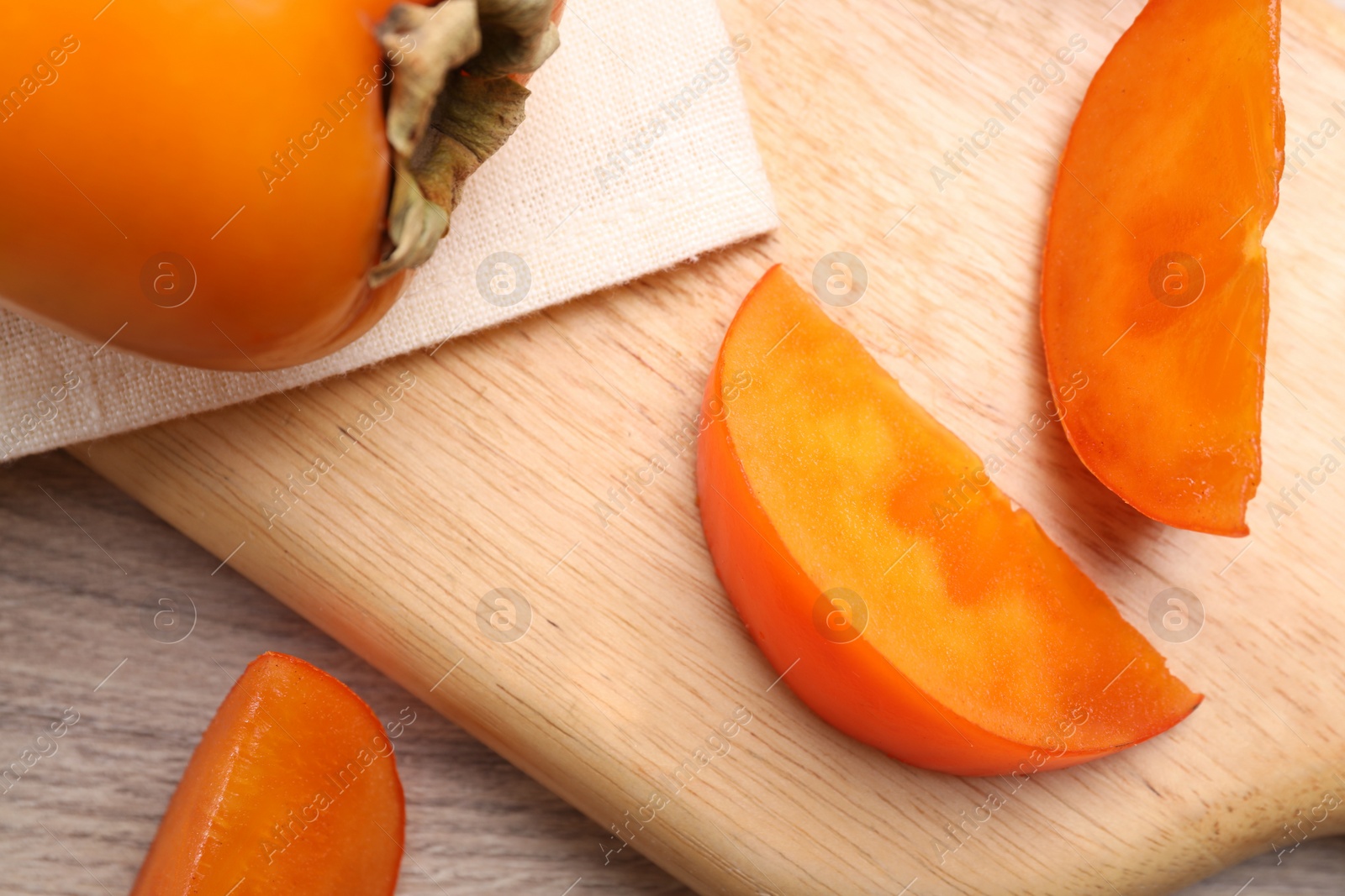 Photo of Delicious ripe persimmons on light wooden table, top view