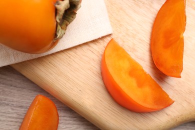 Photo of Delicious ripe persimmons on light wooden table, top view