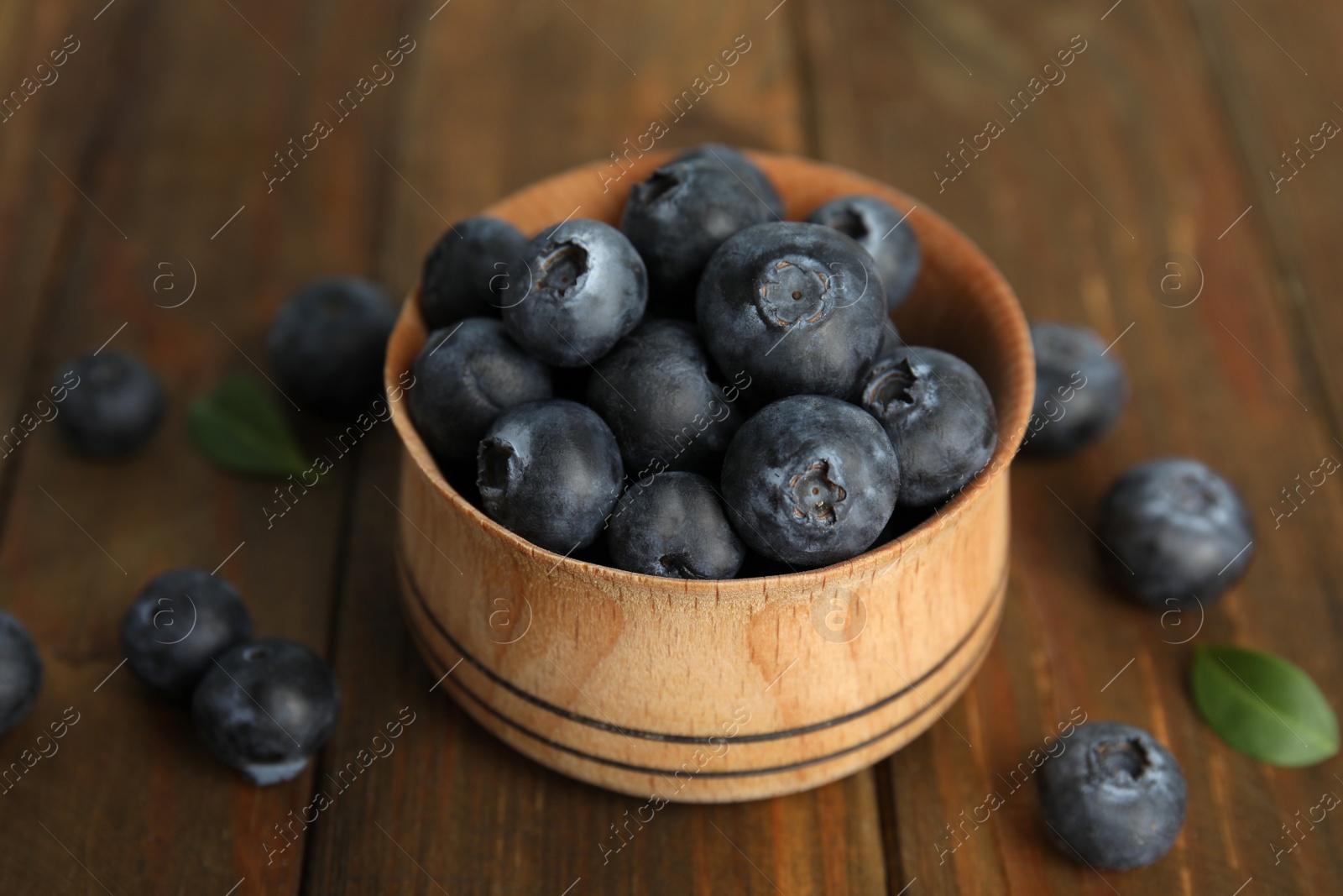 Photo of Fresh ripe blueberries in bowl on wooden table