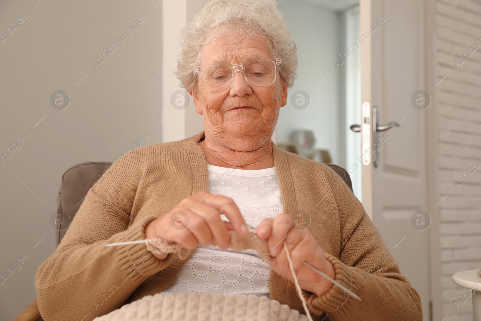 Photo of Elderly woman knitting at home. Creative hobby