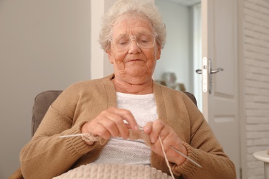 Photo of Elderly woman knitting at home. Creative hobby