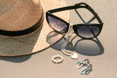 Photo of Stylish hat, sunglasses and jewelry on grey surface, closeup