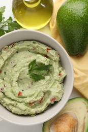 Photo of Delicious guacamole and ingredients on white table, flat lay