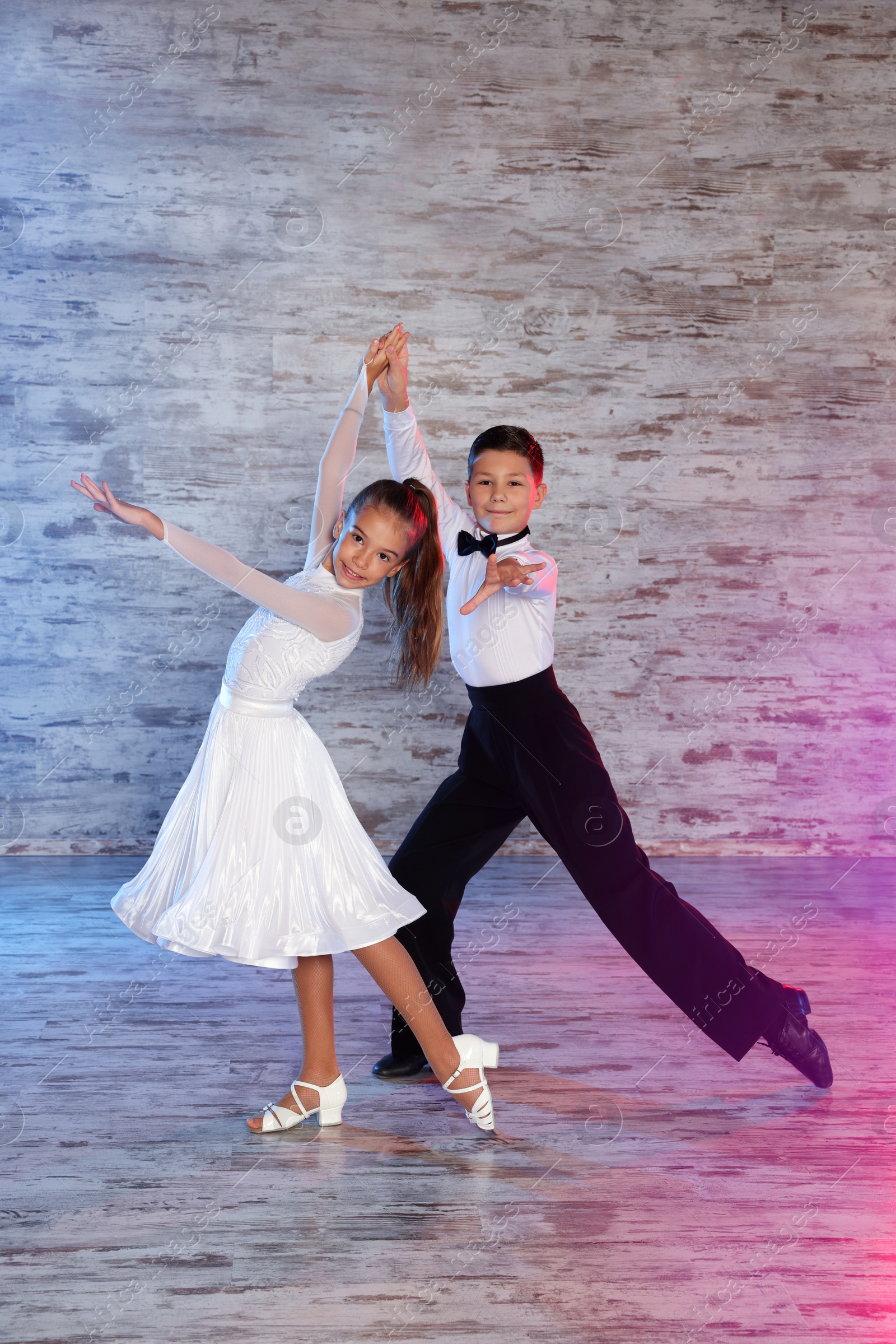 Photo of Beautifully dressed couple of kids dancing together in studio