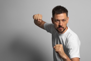 Photo of Man ready to fight on grey background, space for text