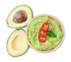 Bowl of delicious guacamole with chili pepper and fresh avocado isolated on white, top view