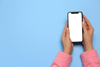 Photo of Woman with smartphone on light blue background, top view. Space for text