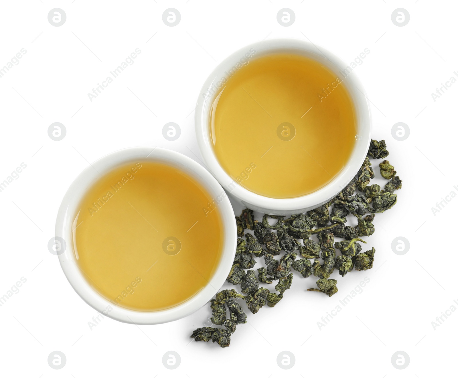 Photo of Cups of Tie Guan Yin oolong and tea leaves on white background, top view