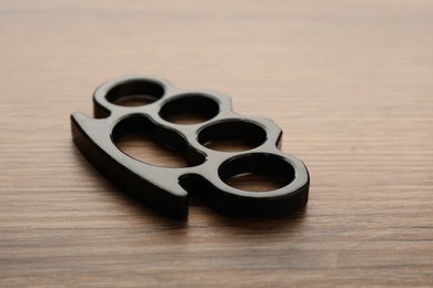 Photo of Black brass knuckles on wooden background, closeup