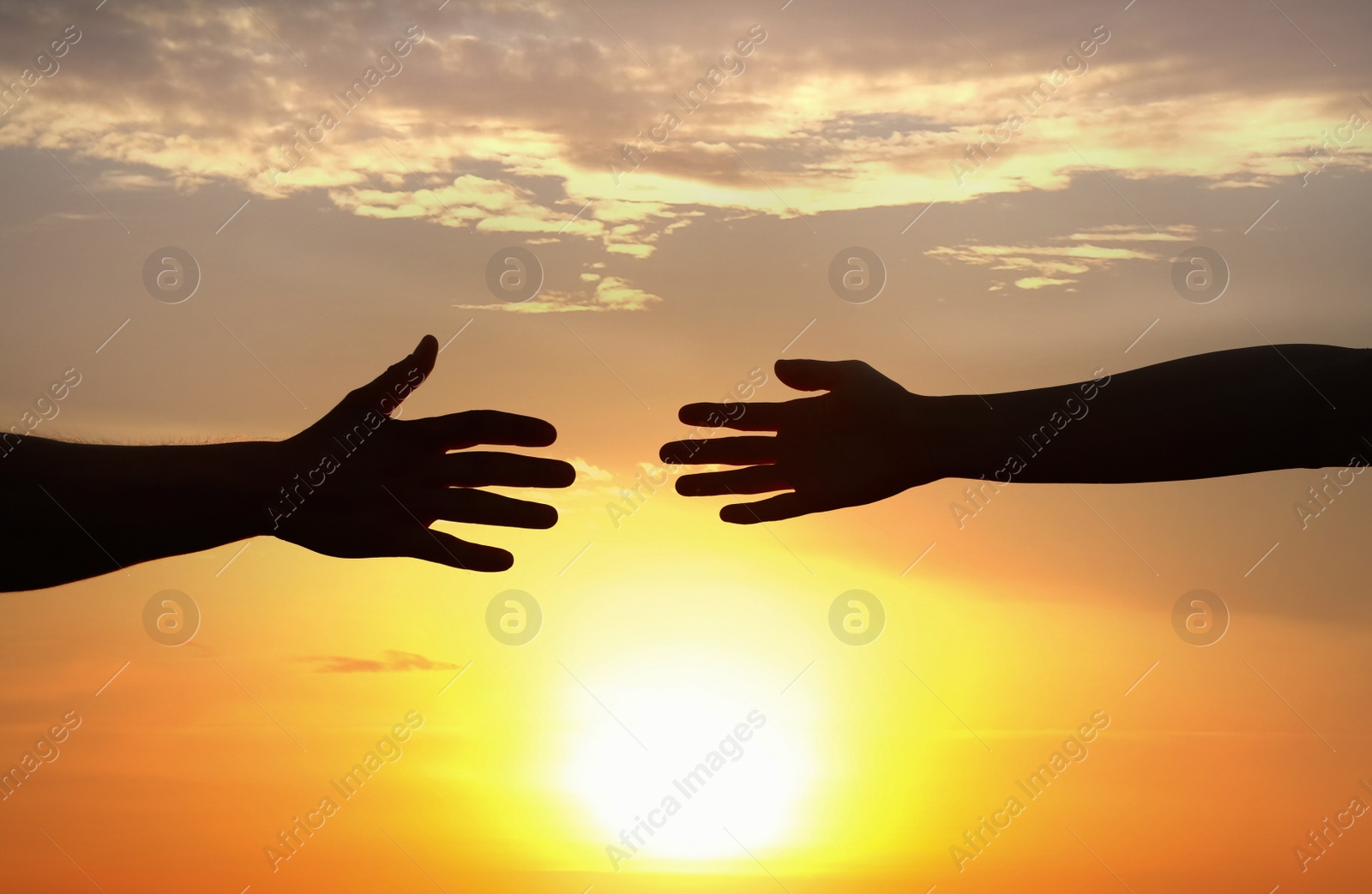 Photo of Man and woman reaching out at sunset. Help and support concept