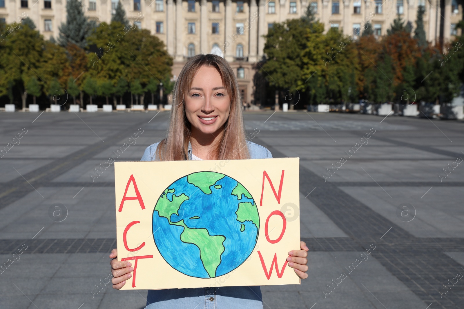 Photo of Young woman with poster protesting against climate change on city street