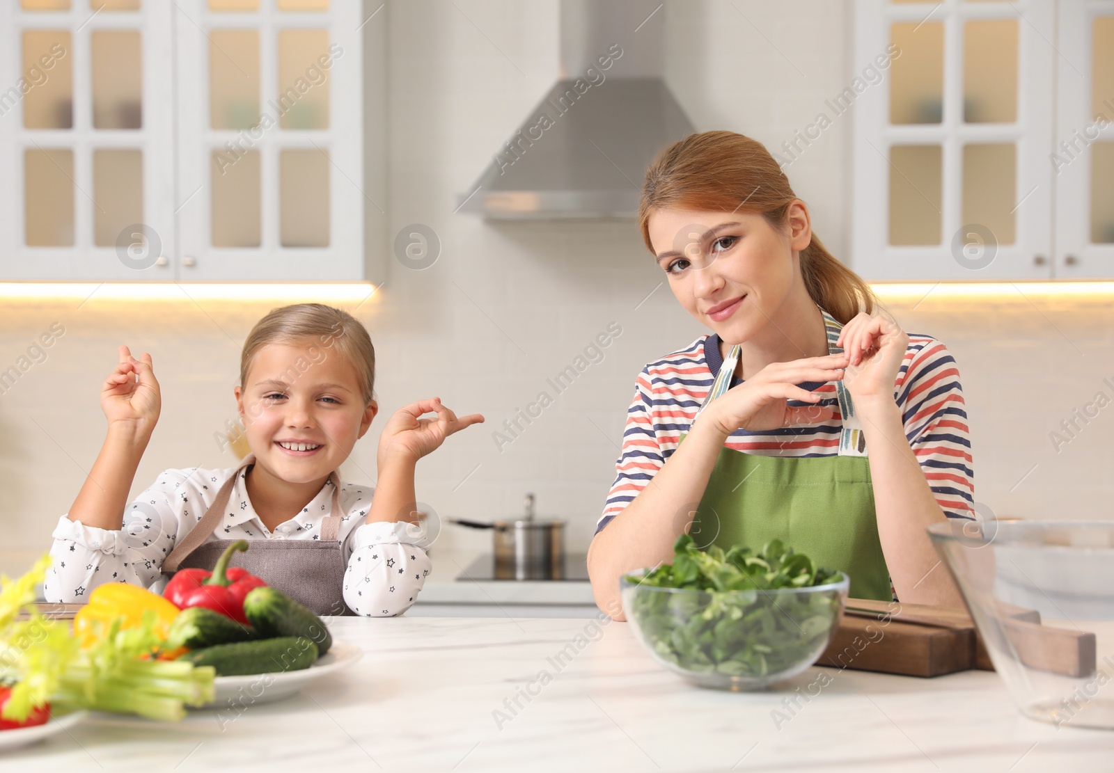 Photo of Mother and daughter cooking salad together in kitchen