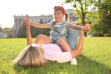 Photo of Happy mother and her child having fun on green grass. Spending time in nature