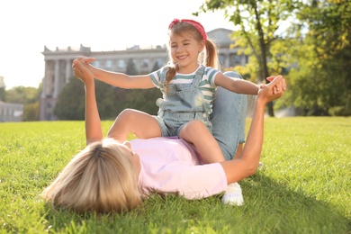 Happy mother and her child having fun on green grass. Spending time in nature