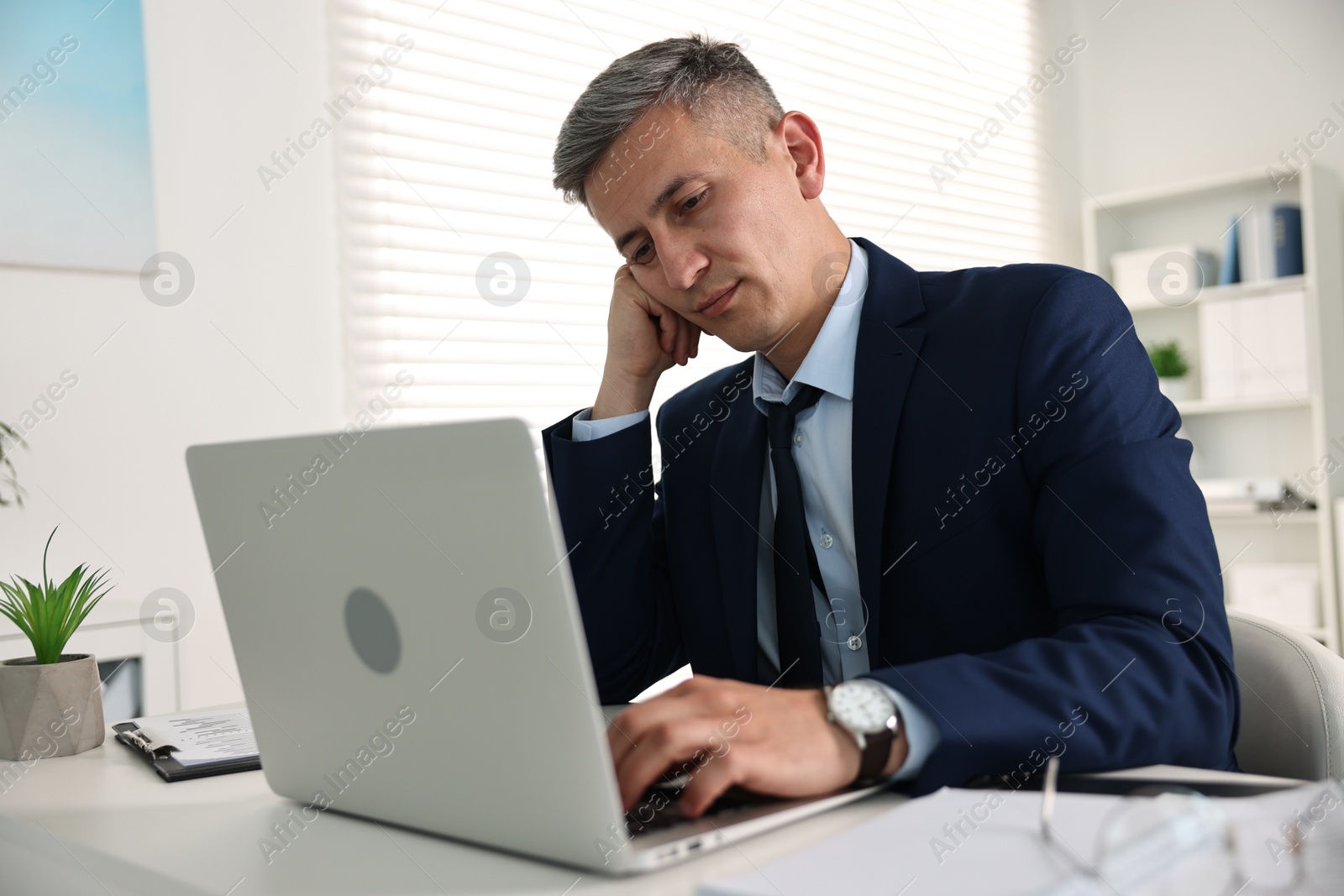 Photo of Sleepy man at table with laptop in office