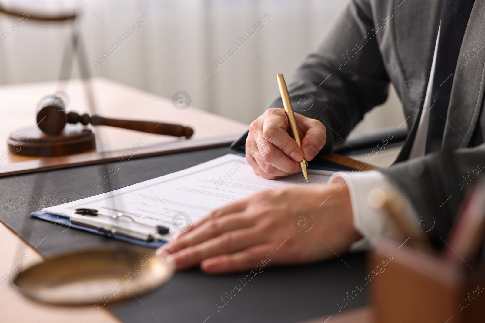Photo of Notary writing notes at wooden table in office, closeup