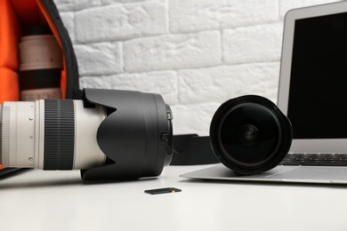 Photo of Laptop and professional photographer's equipment on table indoors