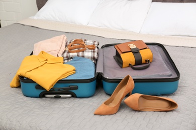 Photo of Suitcase packed for trip on bed in room