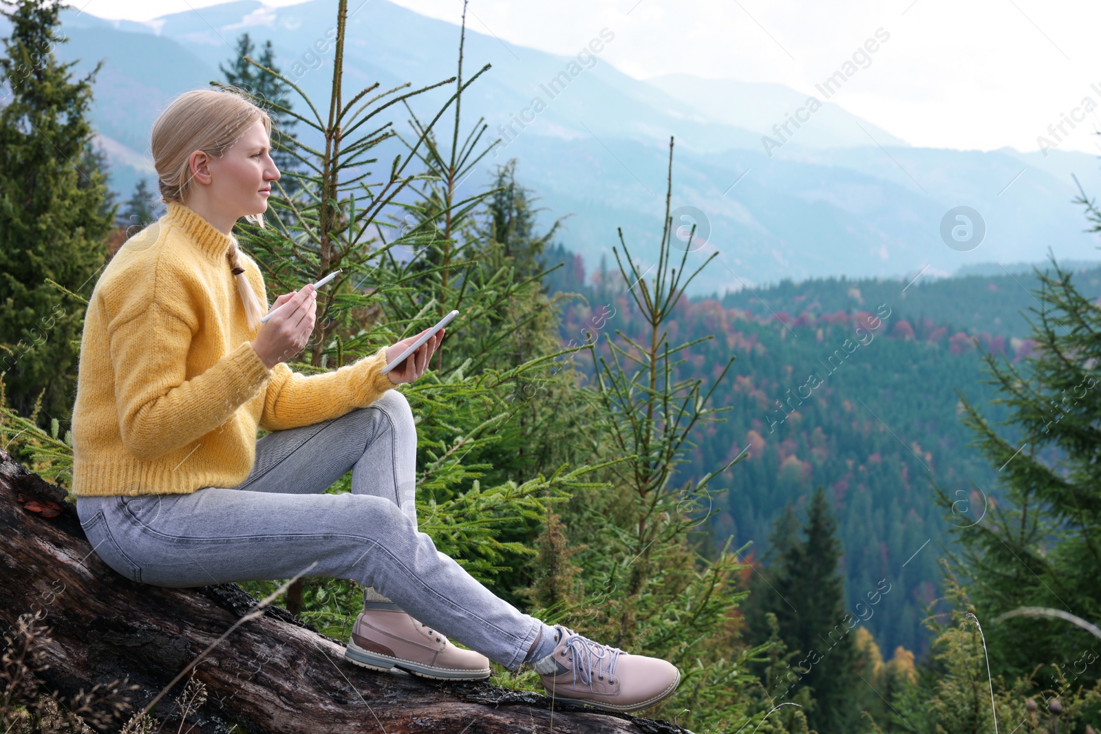 Photo of Young woman drawing with graphic tablet in mountains