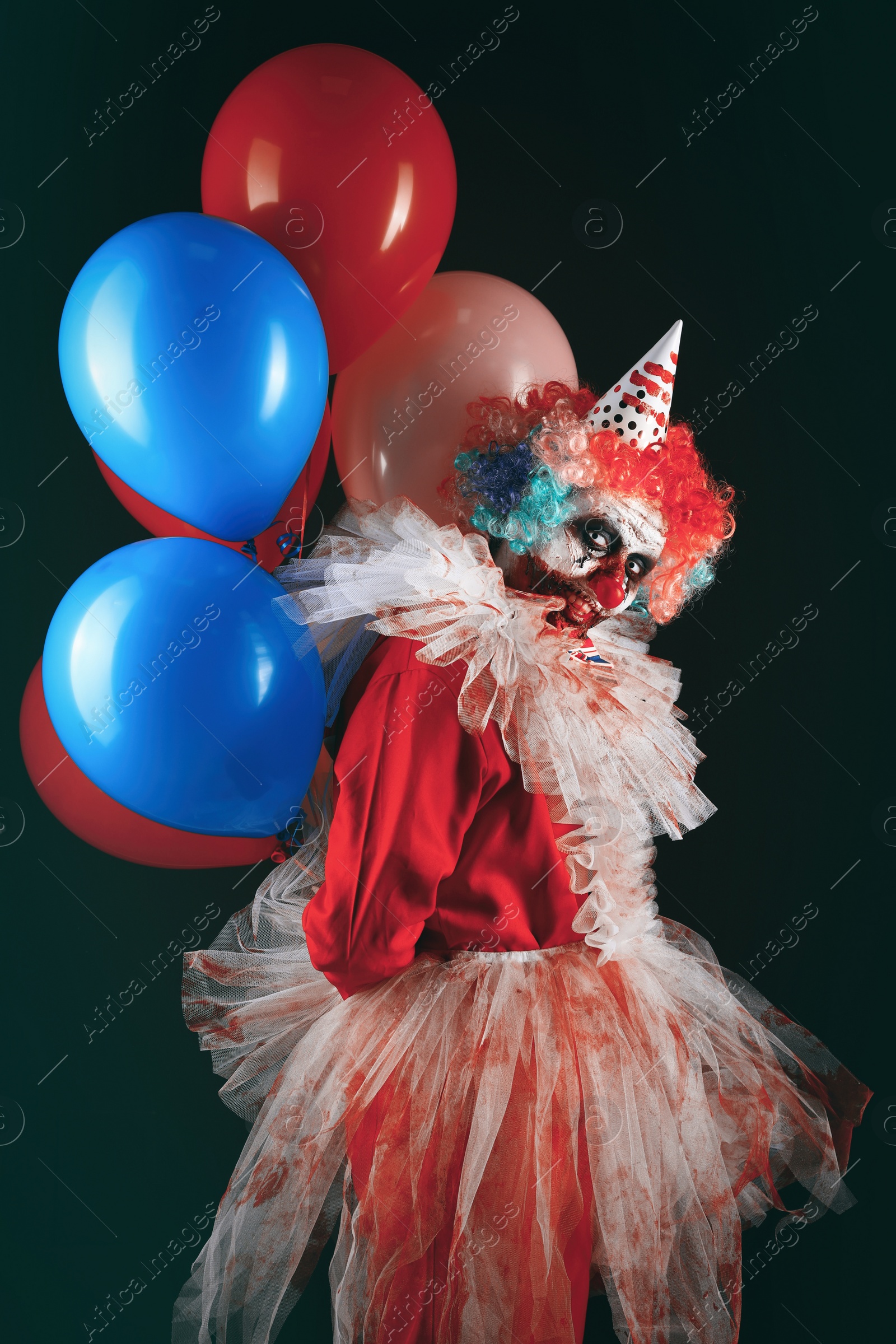 Photo of Terrifying clown with air balloons on black background. Halloween party costume