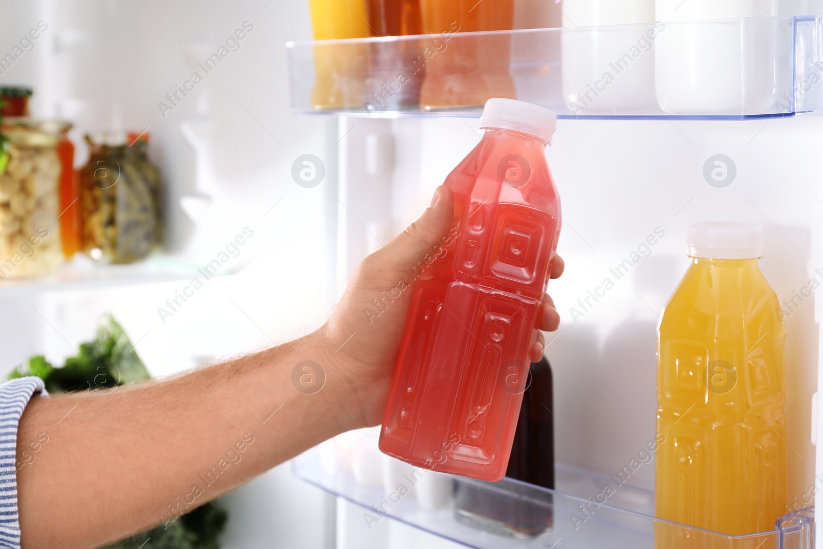 Photo of Man taking bottle with juice out of refrigerator in kitchen, closeup