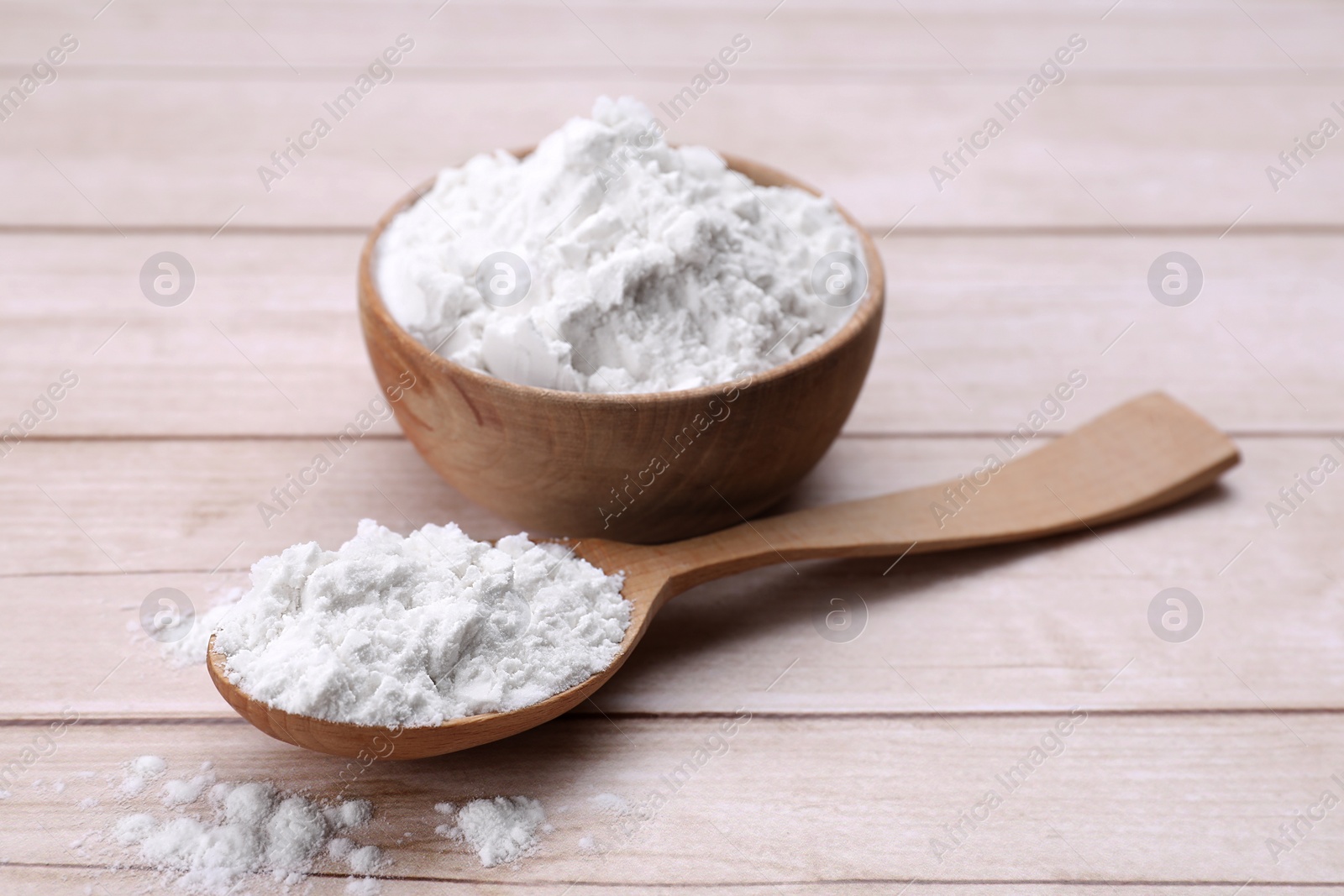 Photo of Bowl and spoon of starch on wooden table, closeup