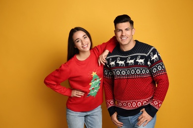 Photo of Couple in Christmas sweaters on yellow background