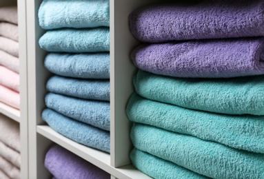 Photo of Colorful towels on shelves, closeup. Bathroom supplies