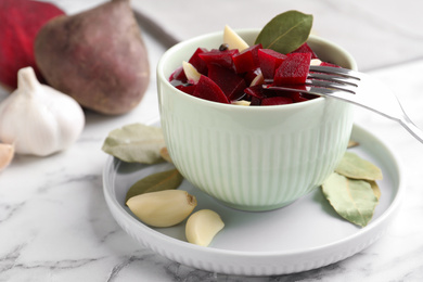 Photo of Pickled beets with garlic in bowl on white marble table