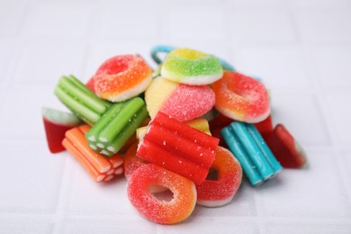 Photo of Pile of tasty colorful jelly candies on white tiled table, closeup