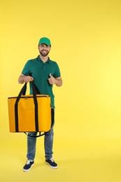 Photo of Young courier with thermo bag on color background, space for text. Food delivery service