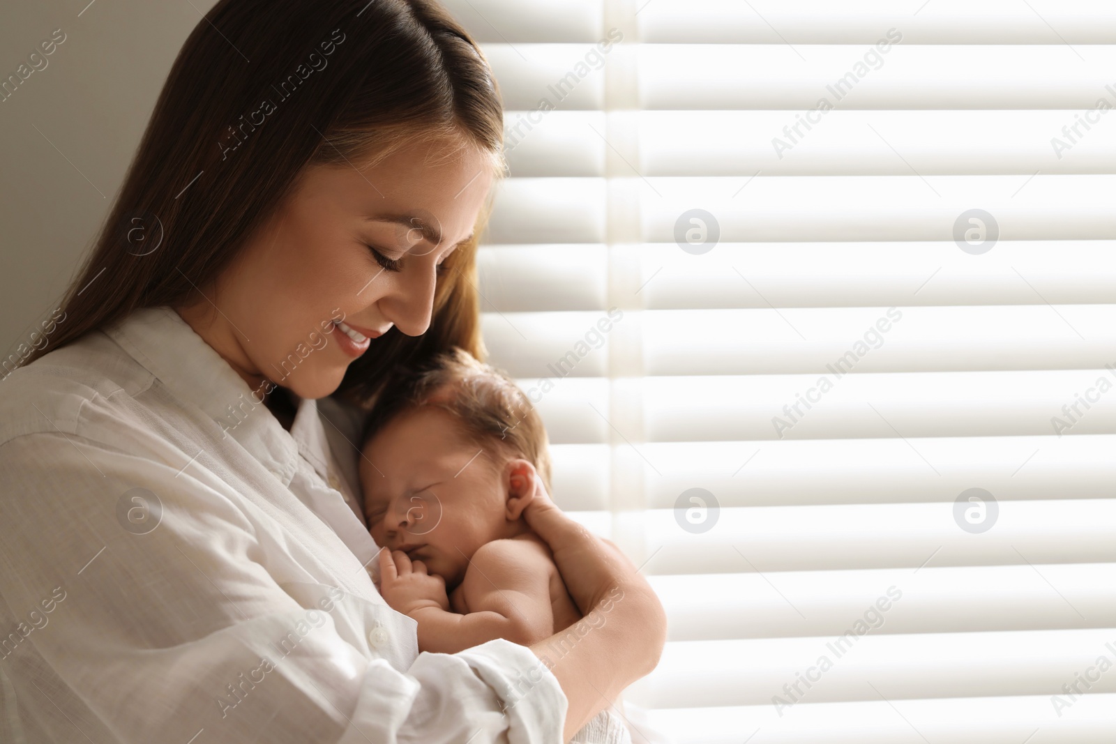 Photo of Mother holding her cute newborn baby indoors. Space for text