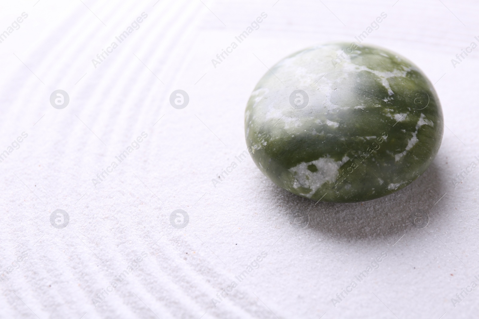 Photo of Stone on sand with pattern. Zen concept