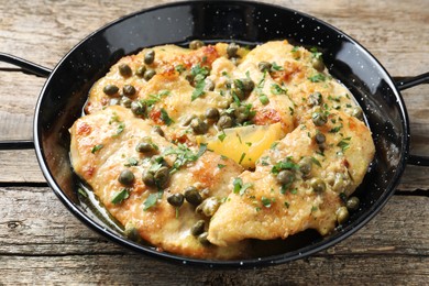 Delicious chicken piccata with herbs on wooden table