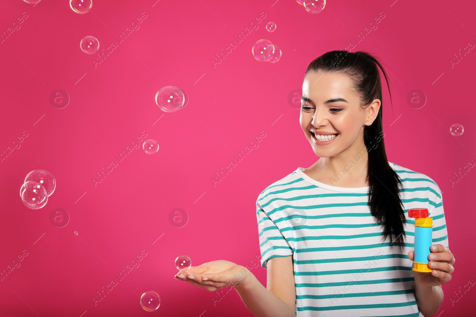 Photo of Young woman having fun with soap bubbles on pink background, space for text