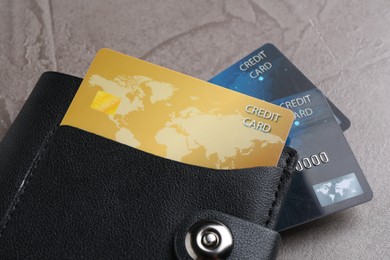 Photo of Credit cards in leather wallet on grey textured table, closeup