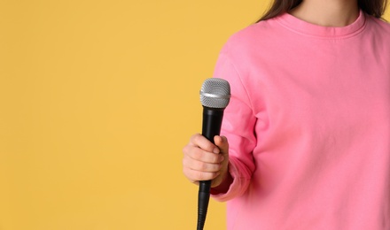 Young woman holding microphone on color background. Space for text