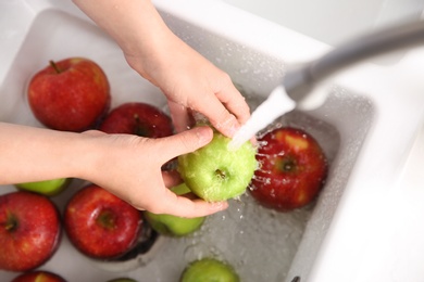 Woman washing fresh apples in kitchen sink, top view