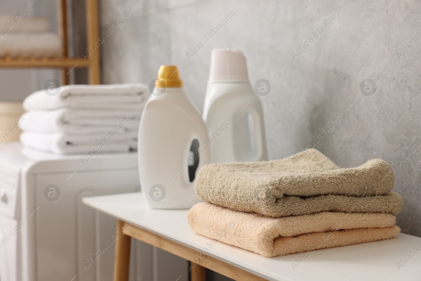 Photo of Soft towels and detergents on bench indoors, closeup