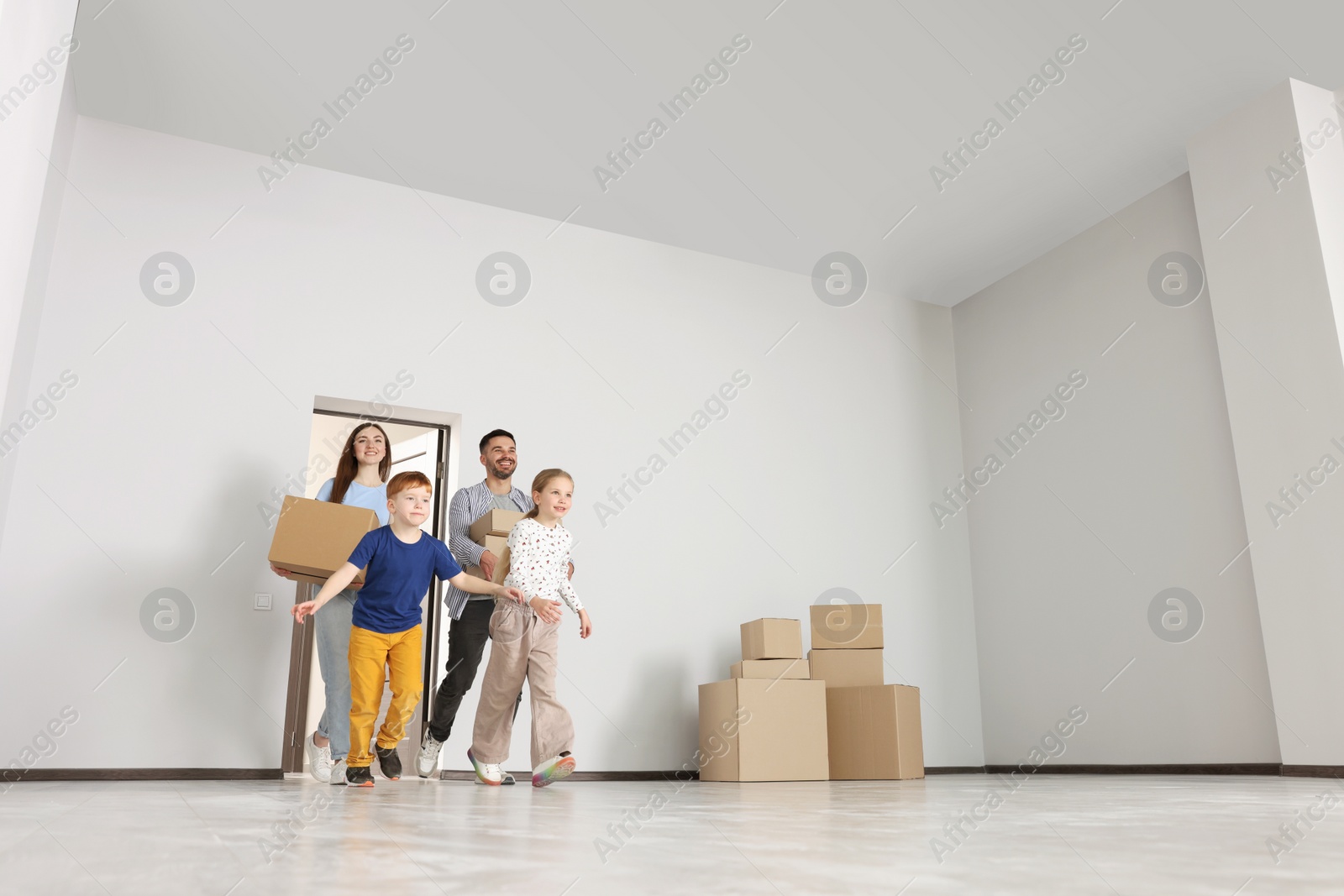 Photo of Happy family with moving boxes entering in new apartment, low angle view. Settling into home