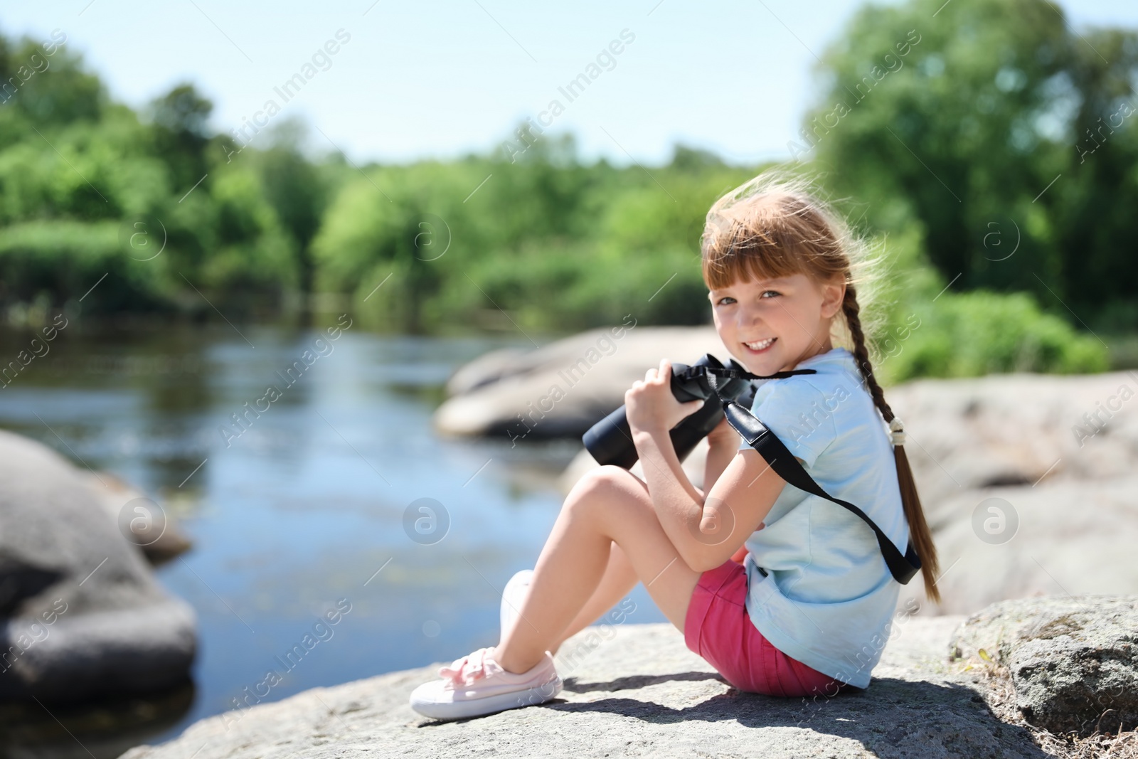 Photo of Little girl with binoculars outdoors. Summer camp