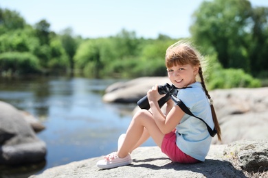 Little girl with binoculars outdoors. Summer camp