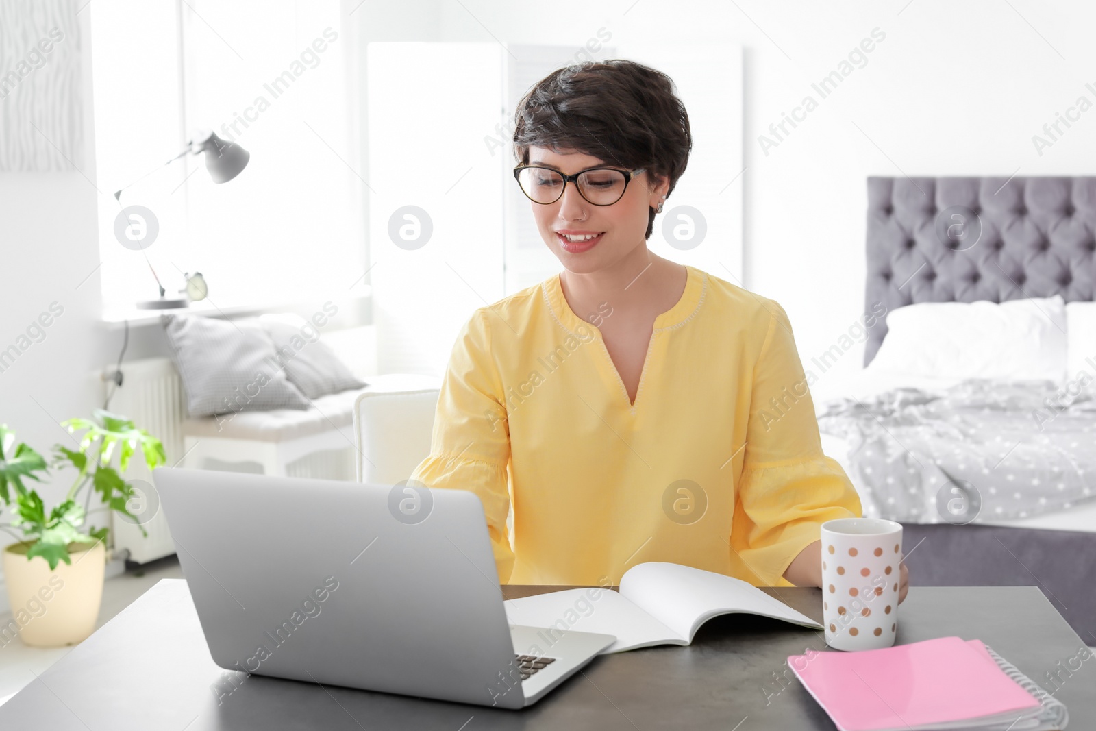 Photo of Young woman working with laptop at desk. Home office