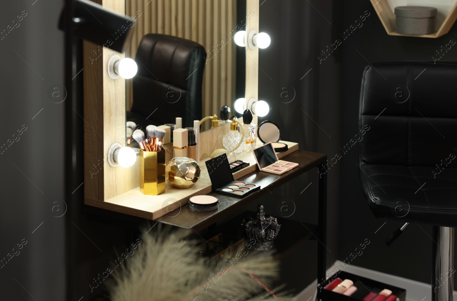 Photo of Makeup room. Stylish mirror with light bulbs and beauty products on dressing table indoors