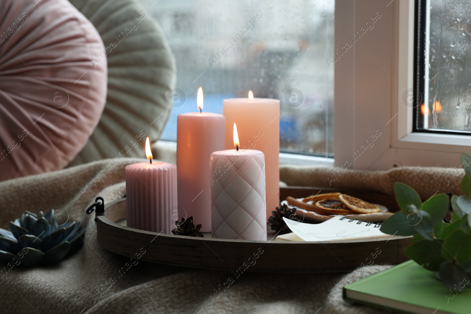 Photo of Tray with burning wax candles and decor on window sill indoors