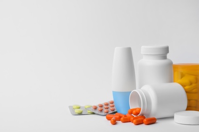 Containers and different pills on white background