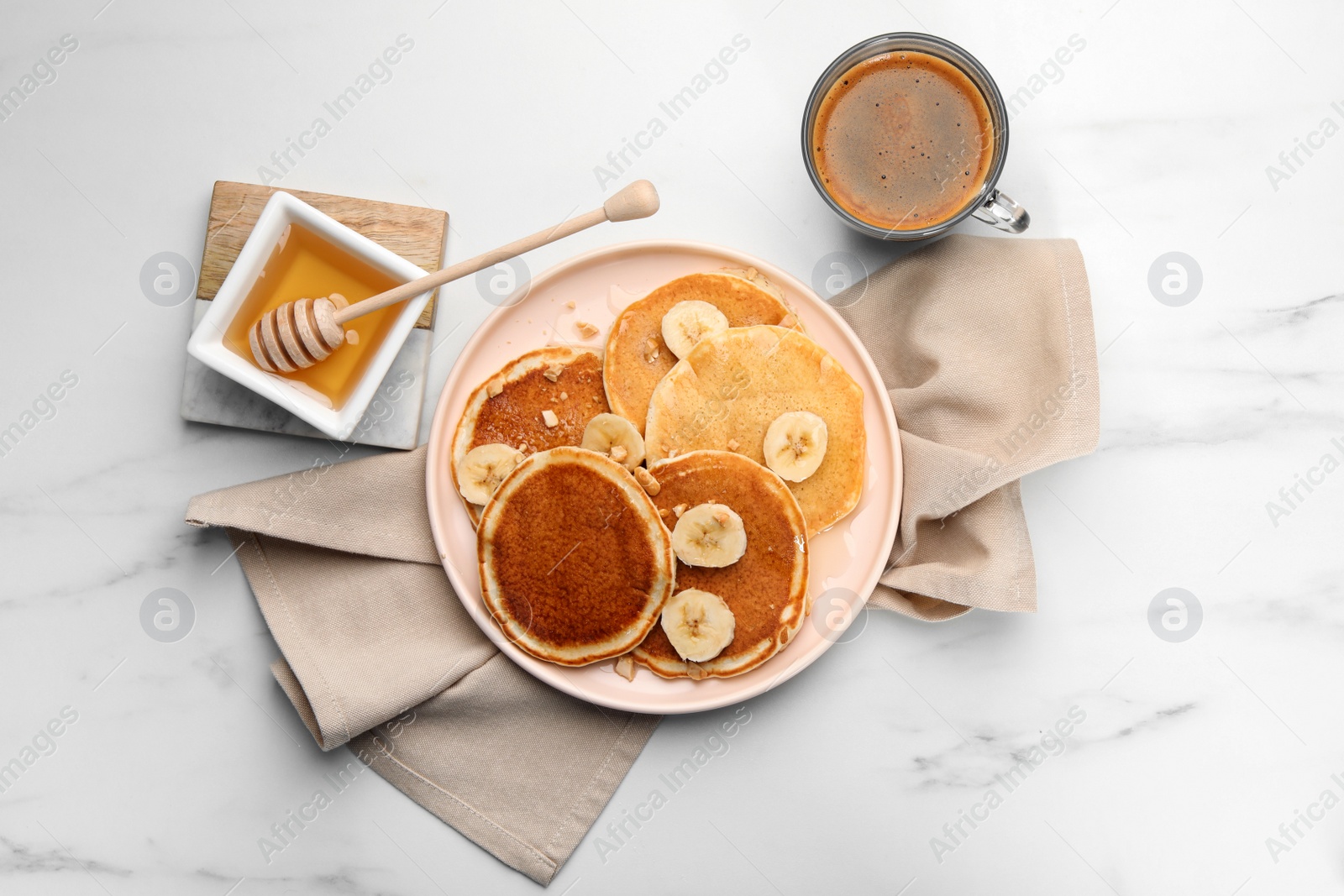 Photo of Tasty pancakes with sliced banana served on white marble table, flat lay