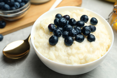 Photo of Delicious rice pudding with blueberries on marble table, closeup