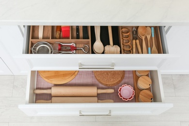 Open drawers with cutlery and utensils indoors. Order in kitchen