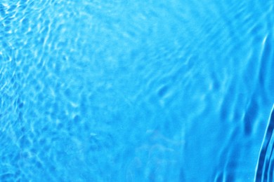 Rippled surface of clear water on light blue background, top view